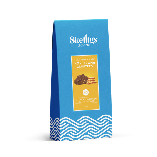 A blue stand-up pouch of Skelligs Chocolate Milk Chocolate Honeycomb Clusters, featuring a yellow label with an image of the chocolate clusters and blue wave patterns at the bottom, set against a plain white background.
